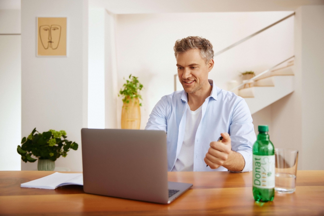 The man sits at the computer and drinks Donat.